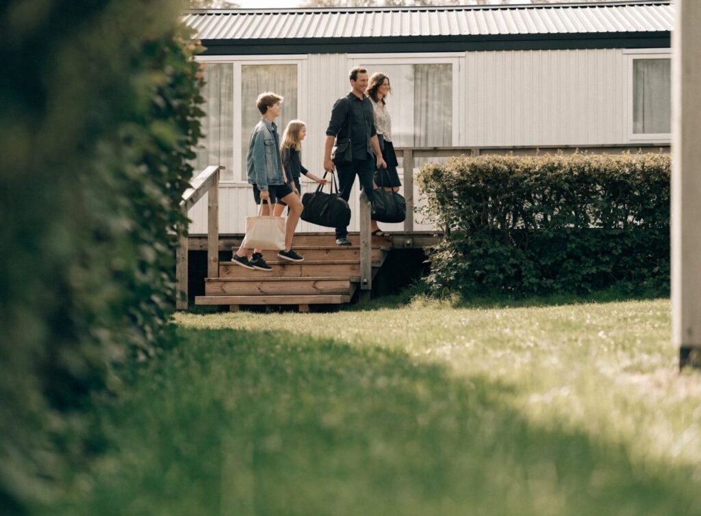 A family arriving at their warm holiday home in natural daylight
